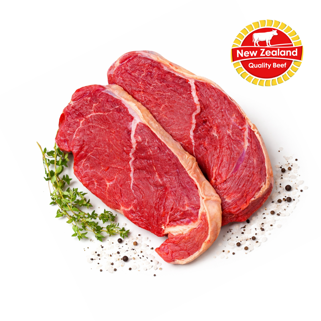 Two raw steaks with herbs and spices on a white background, featuring the New Zealand Quality Beef logo.